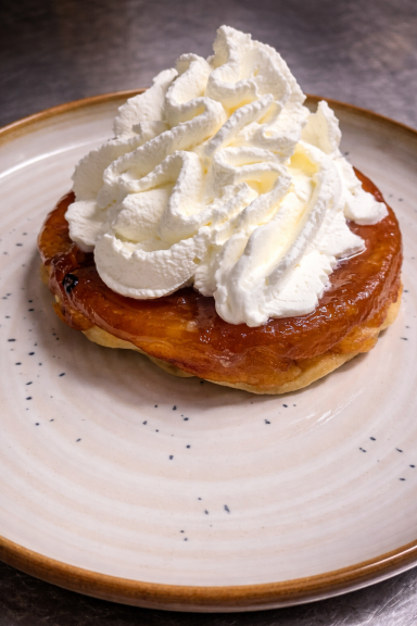 Un doughnut surmonté de crème chantilly sur une assiette.